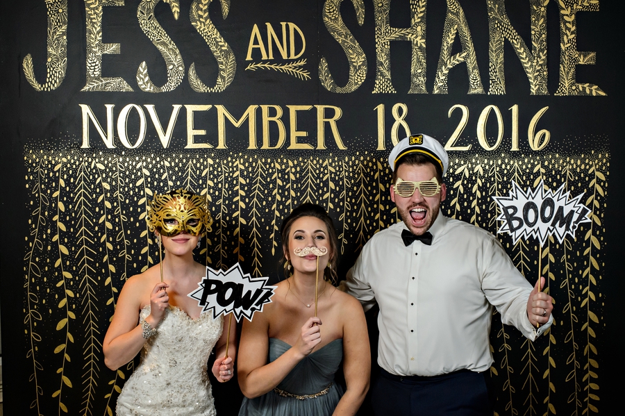 Wedding guests in a fun gold stencled photo booth.